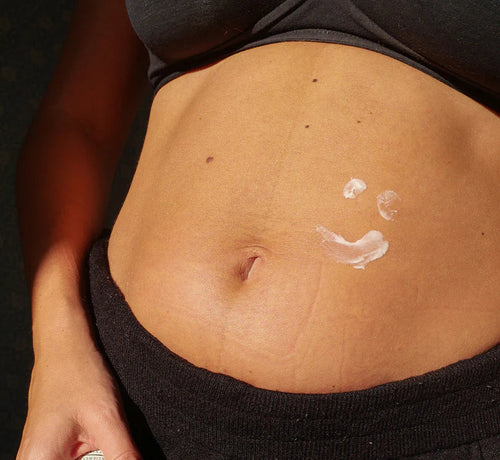 Ventre d'une femme enceinte en début de grossesse, encore peu arrondi, avec une fine couche de crème solaire appliquée. - Mustela Belgium - 1