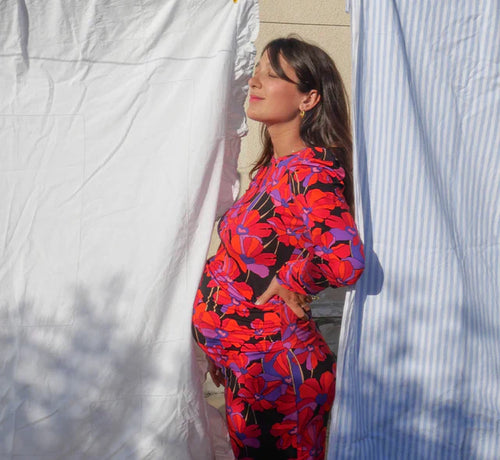 Femme tenant son ventre sur le côté, debout sous les rayons du soleil, exprimant calme et bien-être. - Mustela Belgium - 1