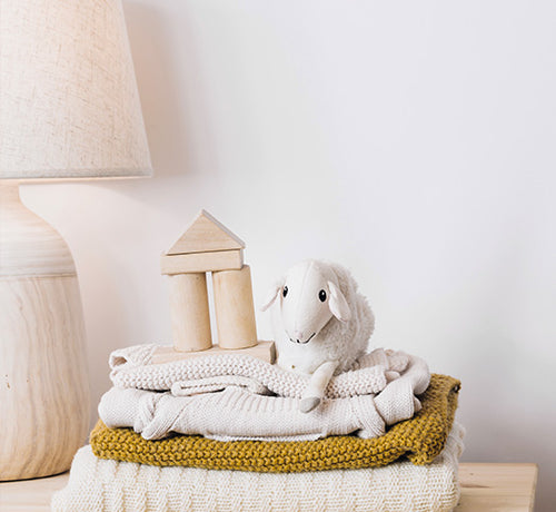 Vêtements bébé pliés sur une commande avec à coté une peluche mouton - Mustela Belgium - 1
