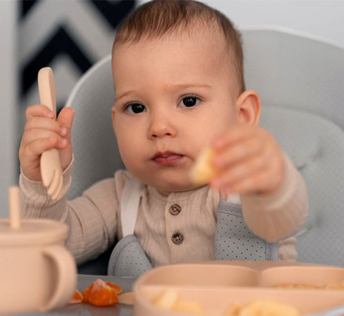 Visage d'un bébé mignon qui mange dans sa chaise haute - Mustela Belgium - 1