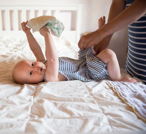 enfant qui tient sa couche et femme qui le change - Mustela Belgium - 1
