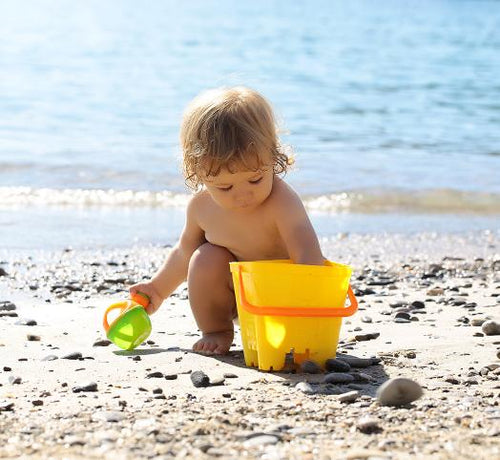Enfant jouant dans le sable avec un saut jaune à la mer - Mustela Belgium - 1