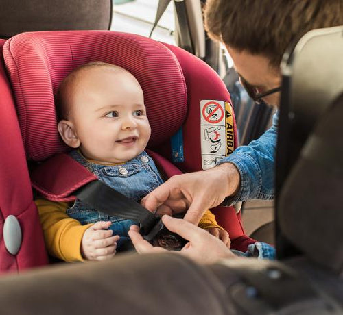 Bébé dans un cosy qui sourit, papa qui attache les sangles, dans la voiture - Mustela Belgium - 1