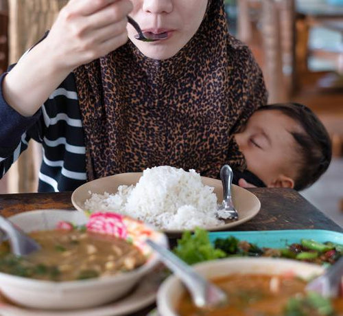 Femme qui mange du riz avec son bébé dans les bras - Mustela Belgium - 1