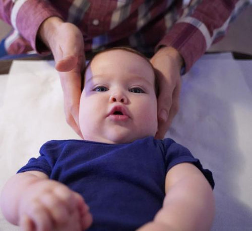 Bébé allongé qui se fait masser la tête - Mustela Belgium - 1