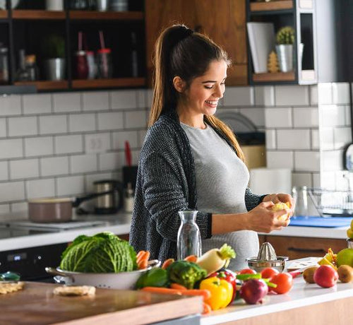 Femme enceinte brune qui cuisine des légumes  - Mustela Belgium - 1