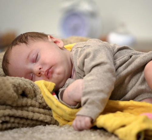 Bébé allongé qui dort paisiblement dans un plaid jaune  - Mustela Belgium - 1