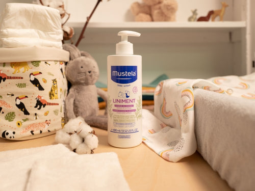 Liniment Mustela pour bébé posé sur une table à langer à côté de produits pour bébé tels que couches et vêtements. - Mustela Belgium - 3