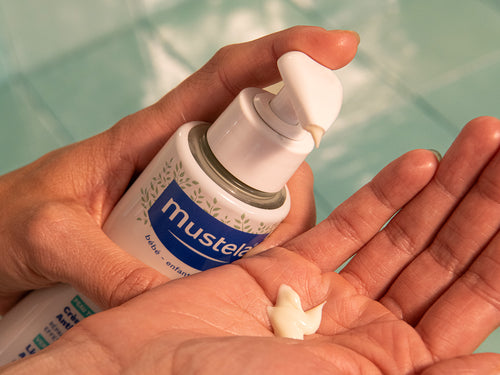 Un flacon avec pompe versant la crème pour atopie stelatopia mustela dans une mains - Mustela Belgium - 3