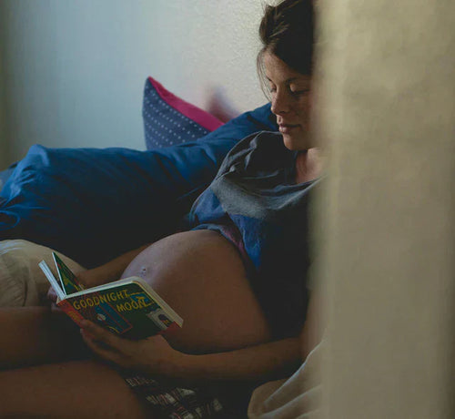 Femme enceinte lisant un livre,avec son ventre de grossesse bien visible. - Mustela Belgium - 1