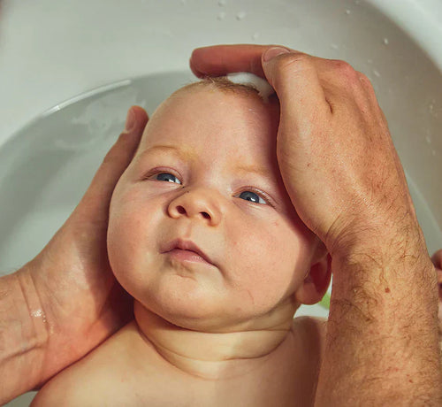 Un papa lave délicatement son petit bébé dans le bain. - Mustela Belgium - 1