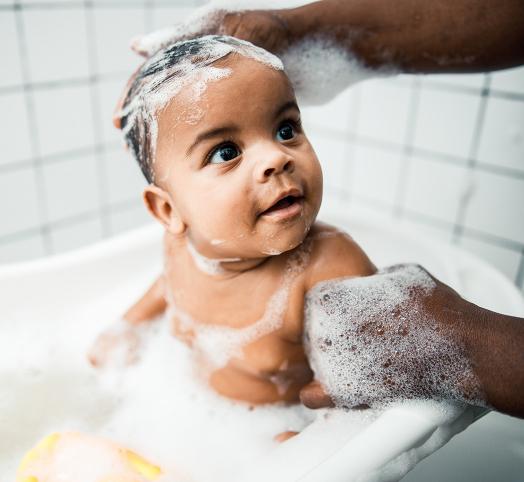 Bébé qui se lave dans un bain avec plein de mousse