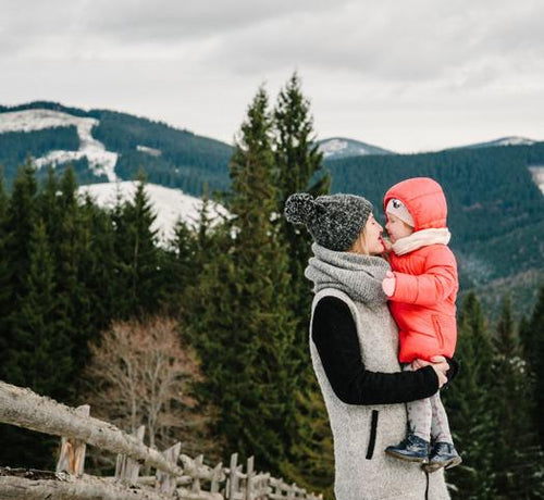 Femme portant un enfant dans les bras à la montagne - Mustela Belgium - 1