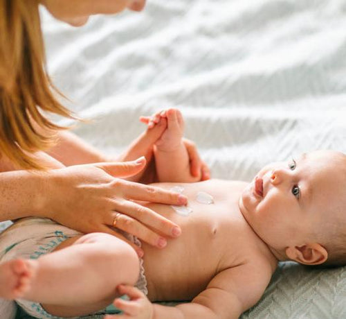 Maman qui applique de la crème sur le vente d'un bébé - Mustela Belgium - 1
