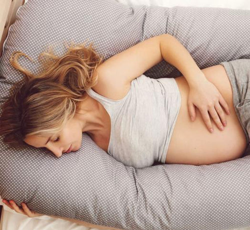 Femme blonde enceinte allongée sur un lit - Mustela Belgium - 1