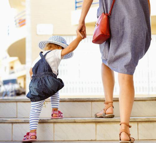 Enfant fille montant une marche de dos avec une femme - Mustela Belgium - 1