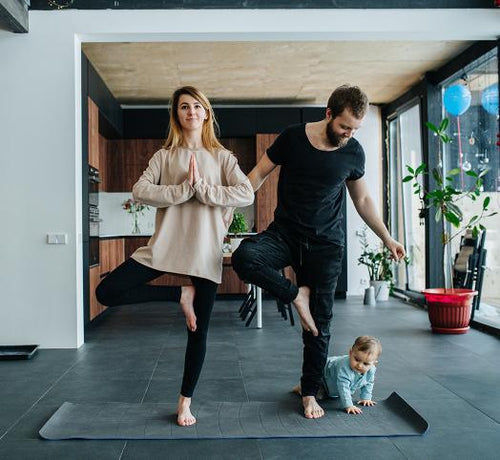 Parents en posture de l'arbre yoga et bébé a coté  - Mustela Belgium - 1