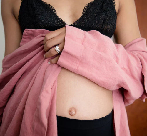 Femme enceinte montrant son ventre rond de grossesse, symbolisant la féminité et l'intimité pendant la grossesse - Mustela Belgium - 1