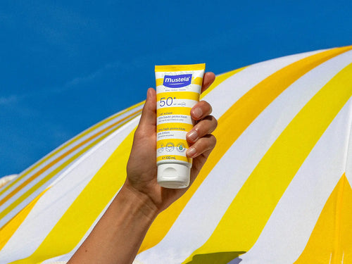 crème solaire tenu dans une mains plage - Mustela Belgium - 6