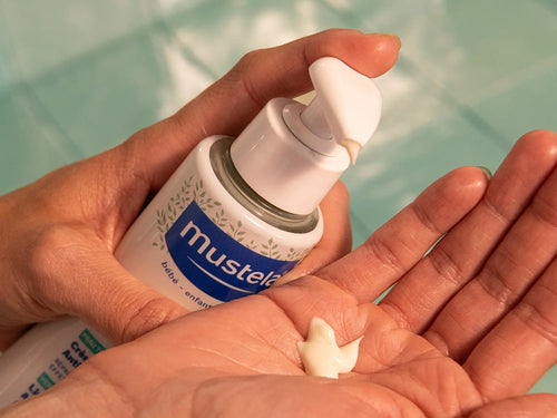 Un flacon avec pompe versant la crème pour atopie stelatopia mustela dans une mains - Mustela Belgium - 8